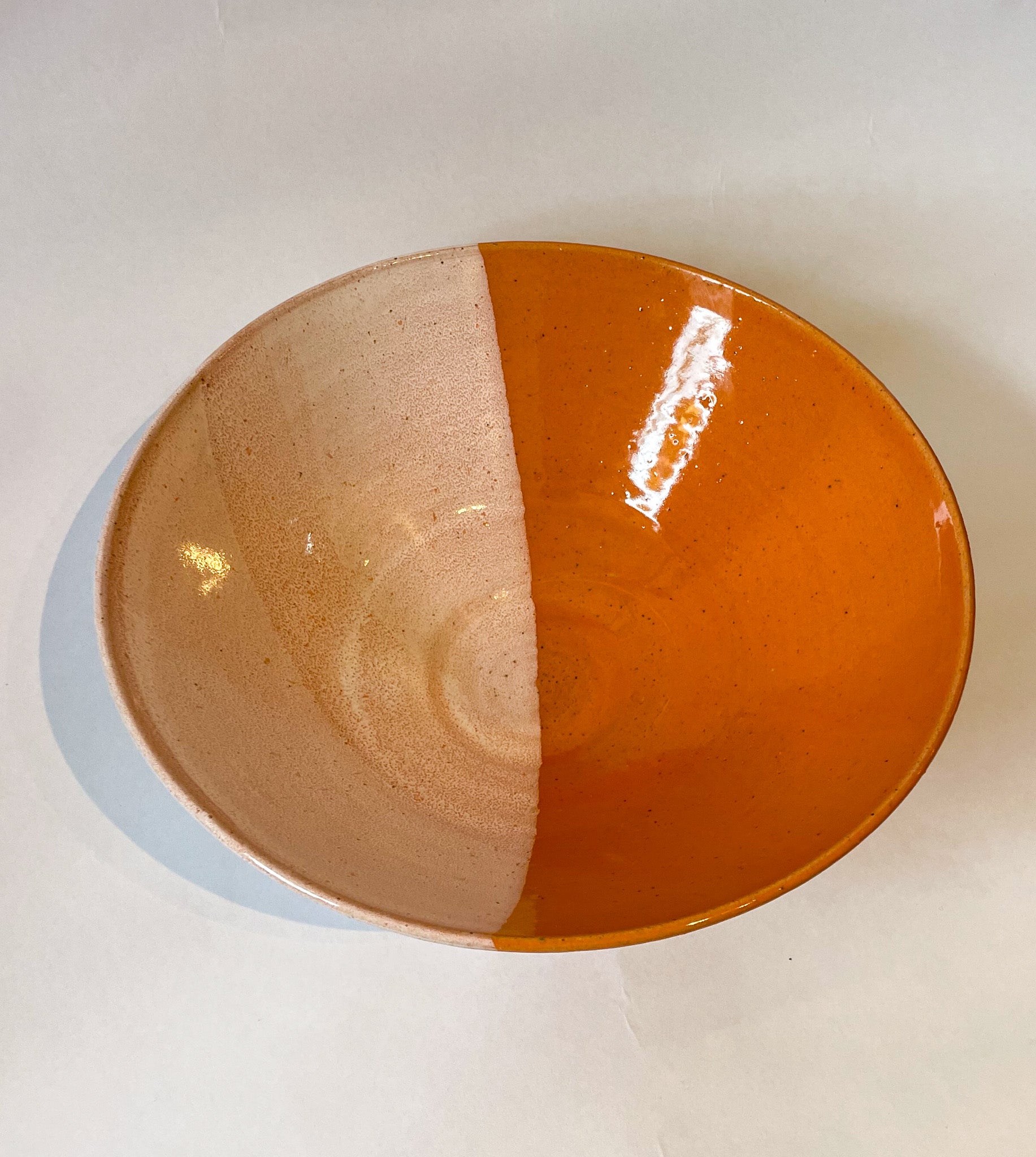 Stoneware bowl with a dipped glaze effect in orange and cream by Frankie Atkinson