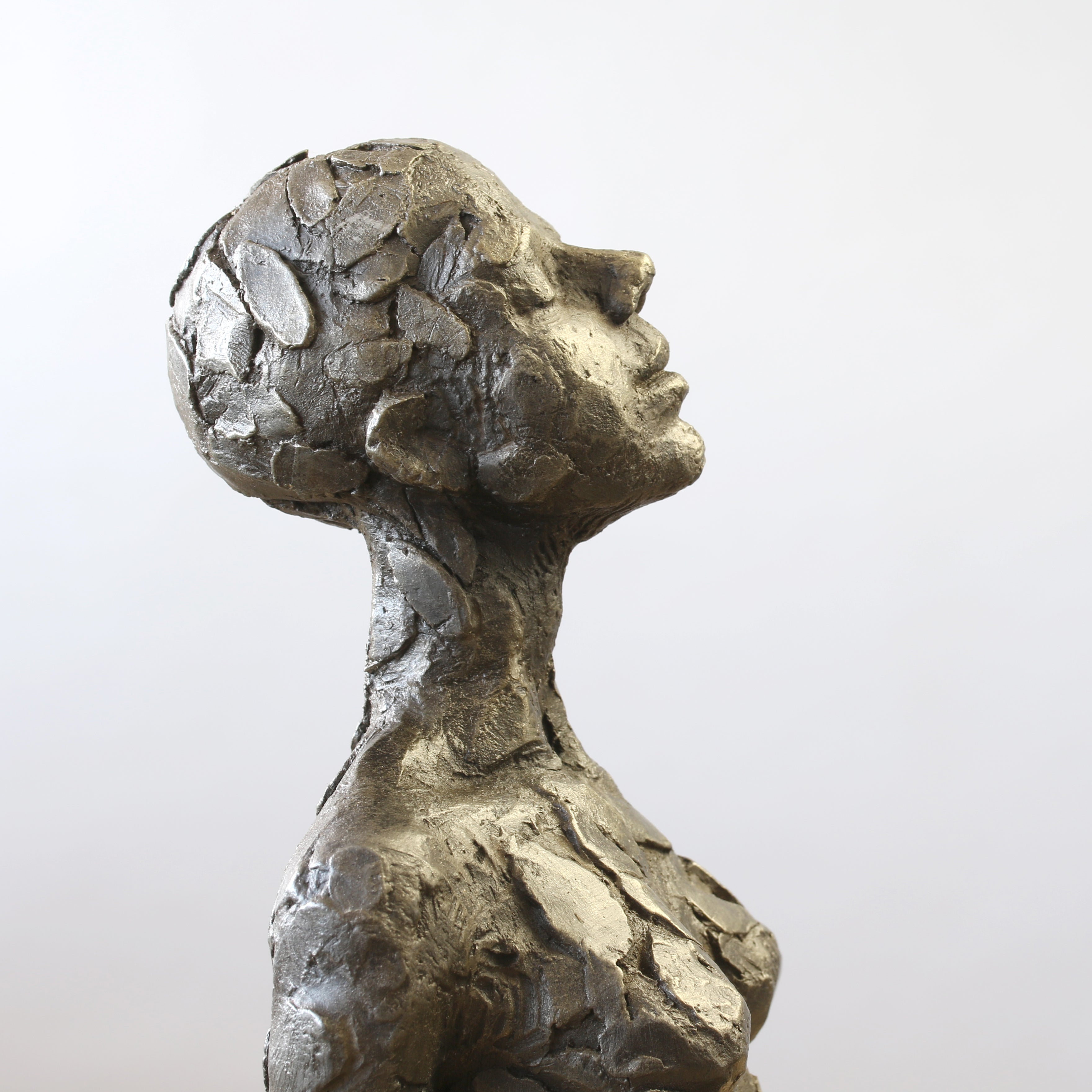 Close up of bronze sculpture sitting in contemplation by Carol Peace.