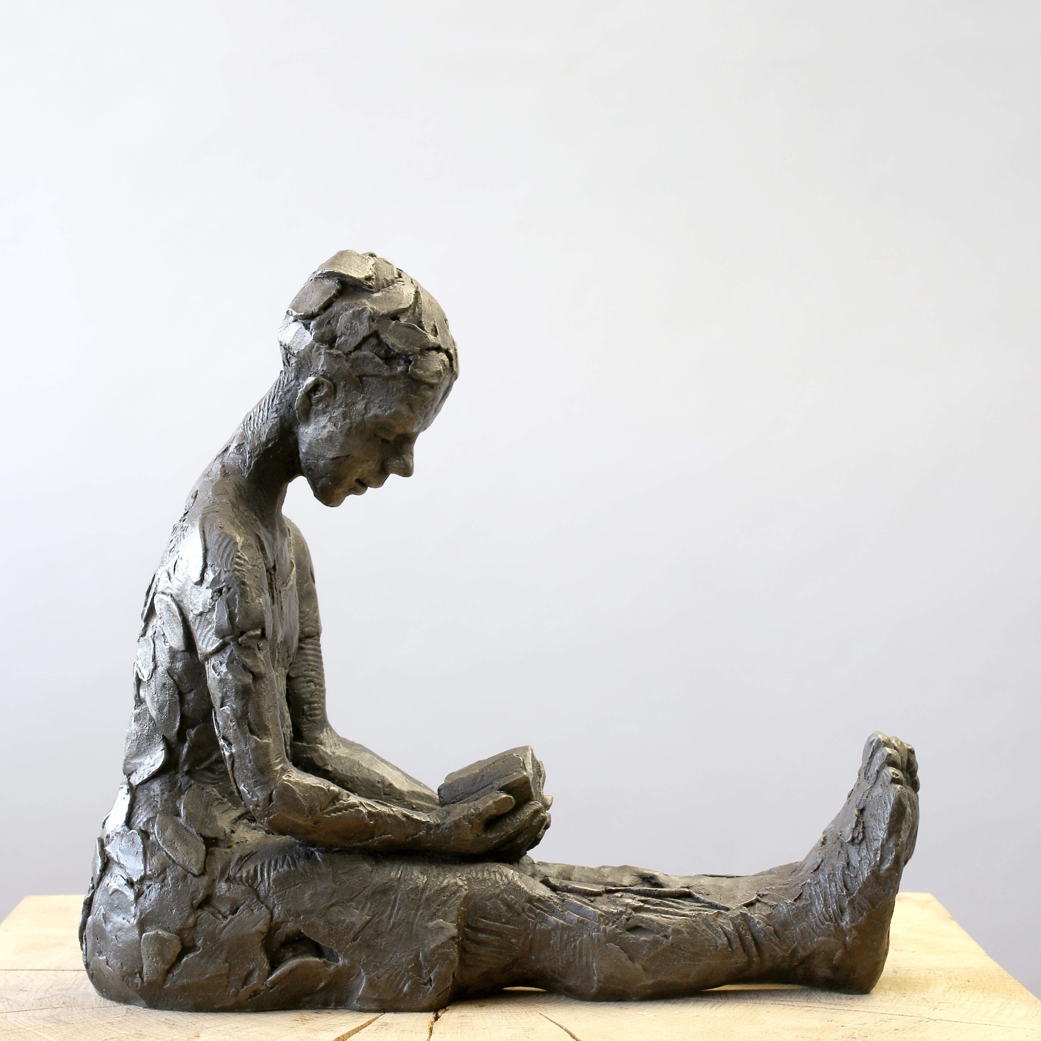 Bronze sculpture of girl reading a book by Carol Peace