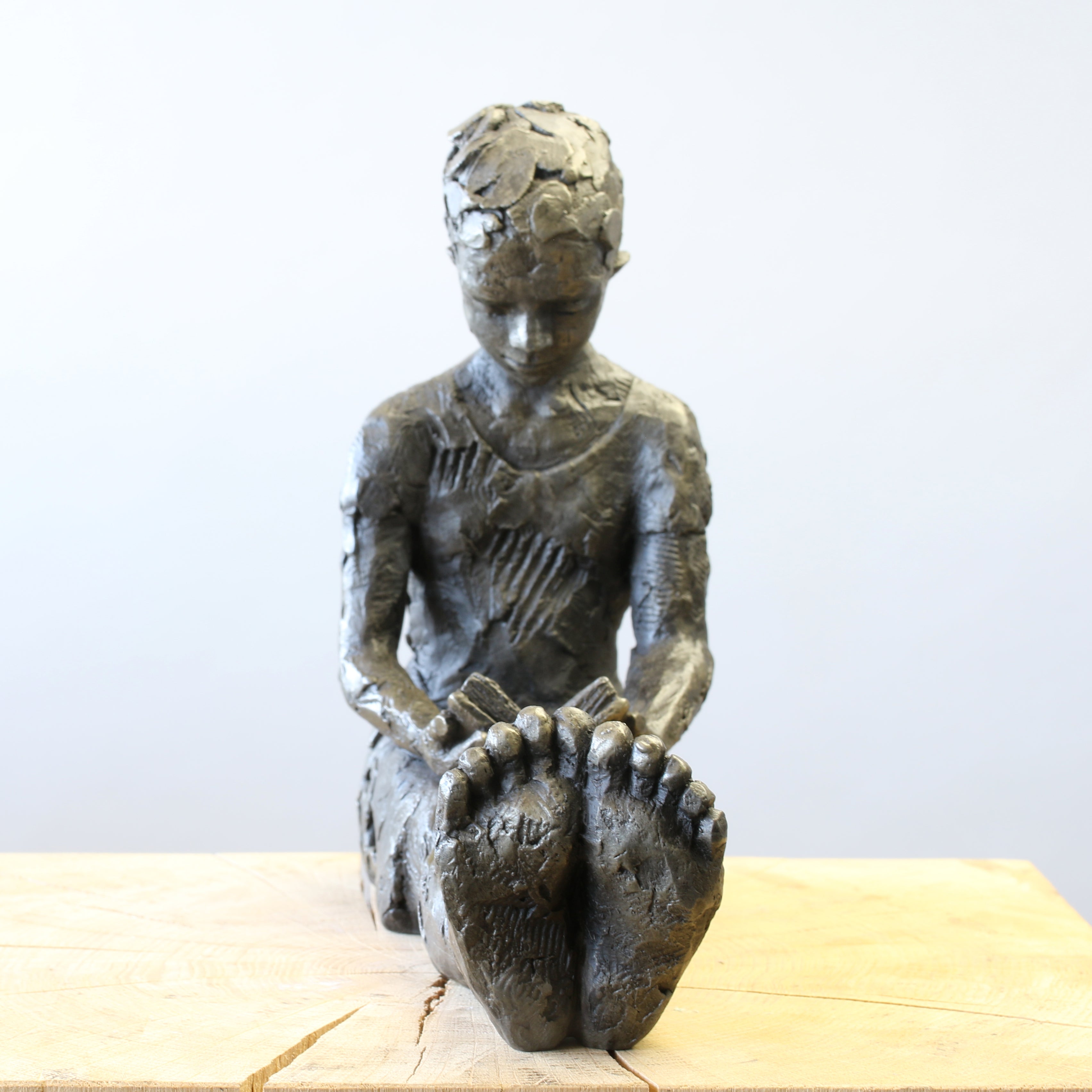 Bronze sculpture of girl reading a book by Carol Peace
