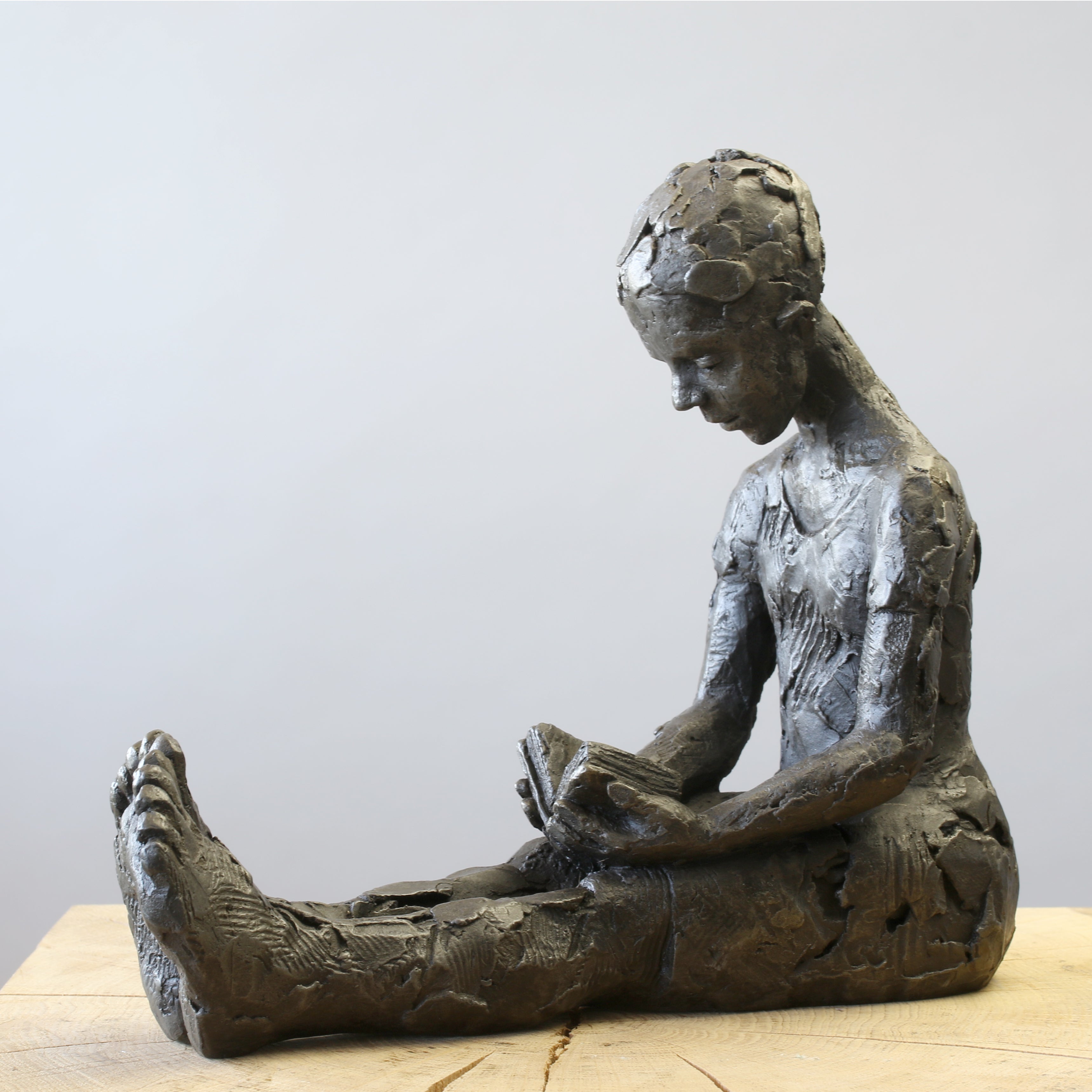 Bronze sculpture of girl reading a book by Carol Peace
