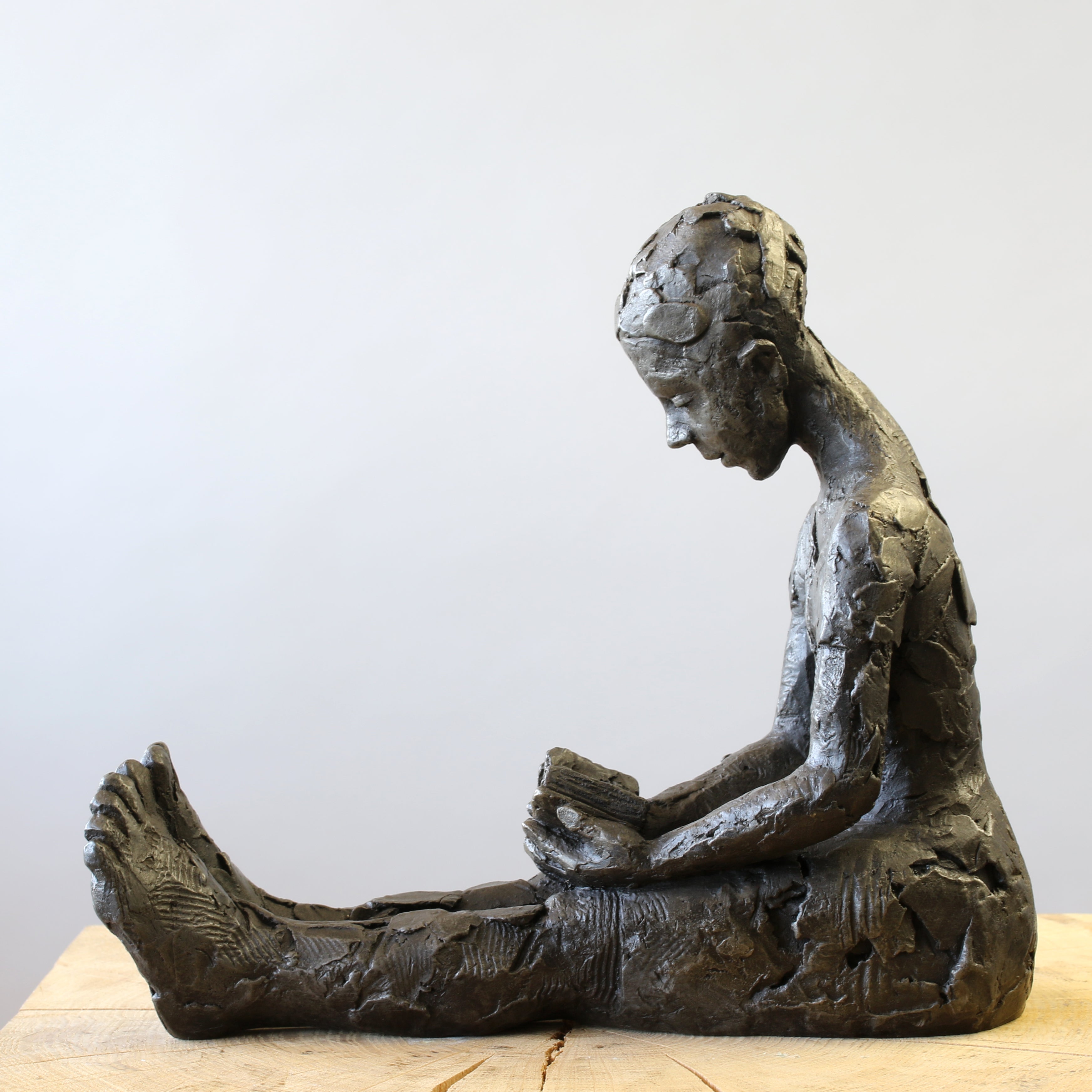 Bronze sculpture of girl reading a book by Carol Peace