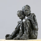 Iron resin sculpture of two huddled figures in embrace by Carol Peace