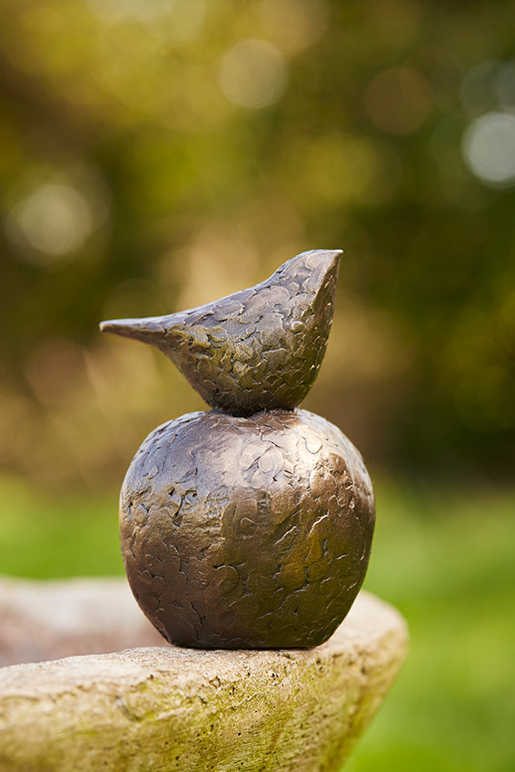 Small bronze sculpture of bird sitting on apple by Caro Burberry